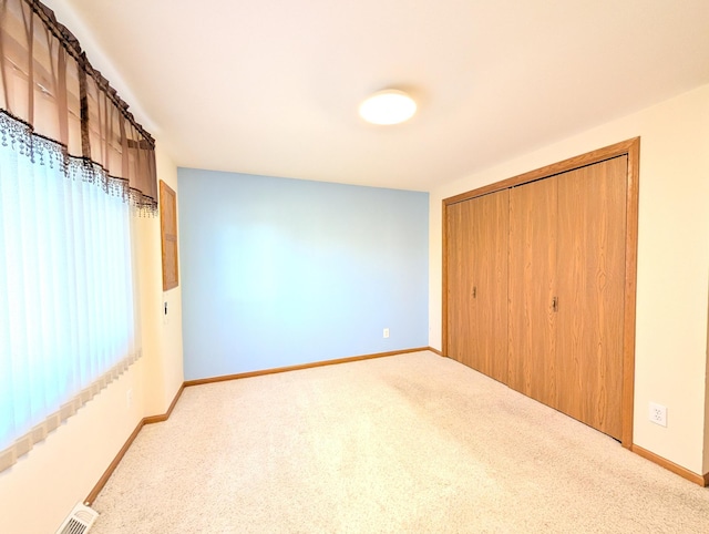 unfurnished bedroom with light colored carpet and a closet