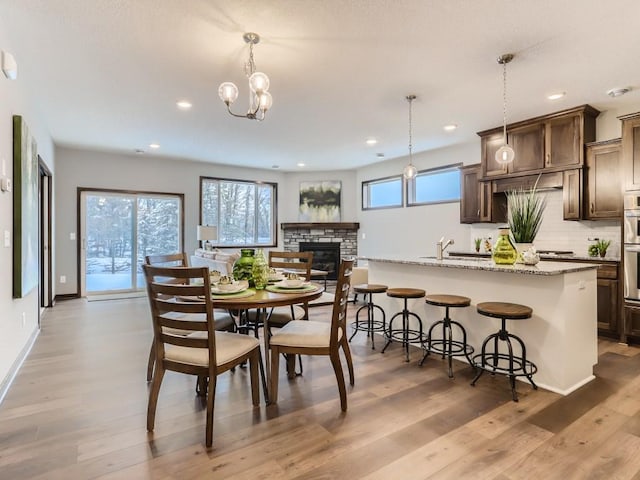 dining room with sink, a fireplace, and light hardwood / wood-style floors