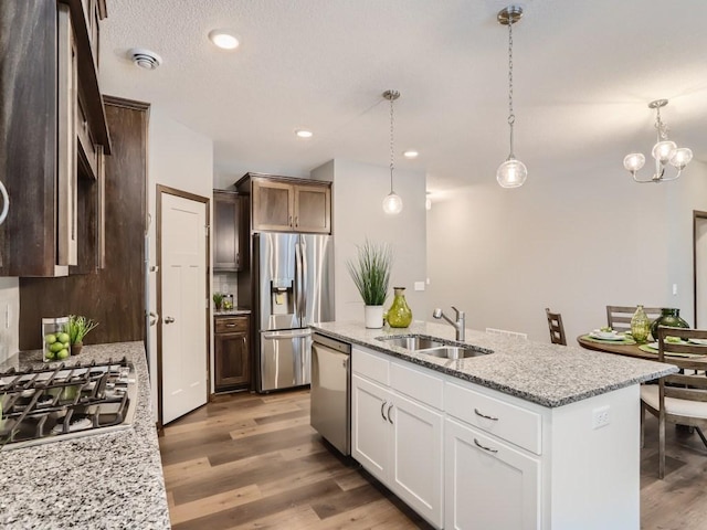 kitchen featuring sink, white cabinetry, decorative light fixtures, stainless steel appliances, and light stone countertops