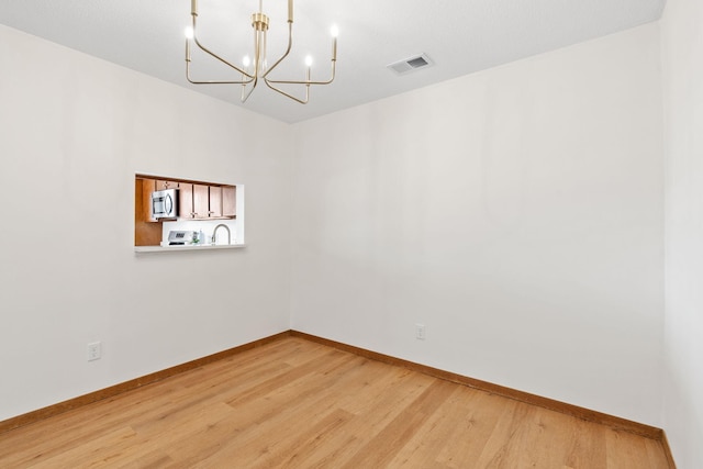 10 94th Cir NW Unit 201, Coon Rapids, MN 55448 - unfurnished room with a chandelier, light wood finished floors, and baseboards