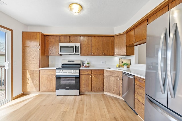 10 94th Cir NW Unit 201, Coon Rapids, MN 55448 - kitchen featuring stainless steel appliances, light wood finished floors, a sink, light countertops, and brown cabinetry