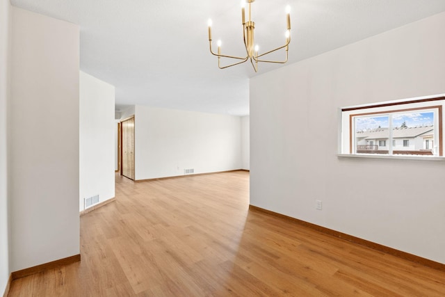 10 94th Cir NW Unit 201, Coon Rapids, MN 55448 - empty room featuring a chandelier, light wood-type flooring, and baseboards
