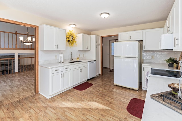 kitchen with sink, hanging light fixtures, white appliances, light hardwood / wood-style floors, and white cabinets