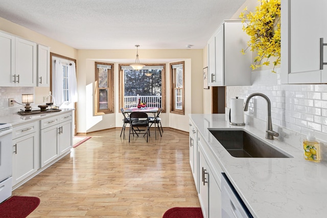 kitchen featuring hanging light fixtures, white cabinetry, sink, and light hardwood / wood-style floors