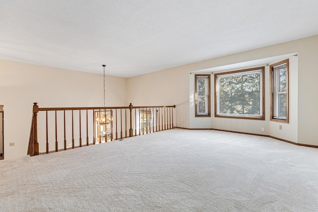 unfurnished room with carpet floors, a textured ceiling, and a notable chandelier