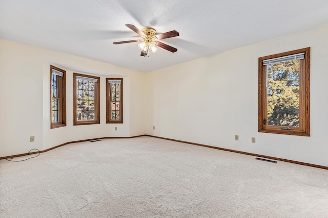 empty room with ceiling fan, carpet floors, and a textured ceiling