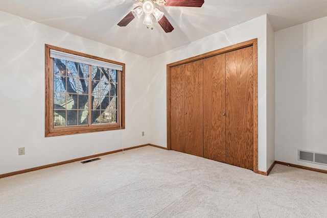 unfurnished bedroom featuring ceiling fan, light colored carpet, a closet, and a textured ceiling