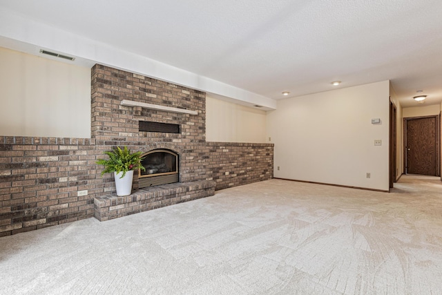 unfurnished living room with light carpet, a fireplace, and a textured ceiling