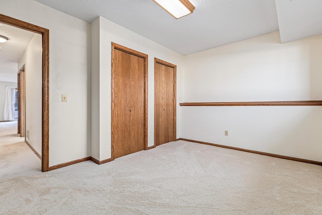 unfurnished bedroom with light colored carpet and two closets