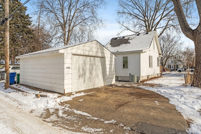 view of snowy exterior featuring central AC, a garage, and an outdoor structure