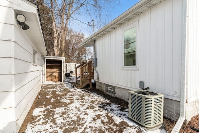 snow covered property with central AC