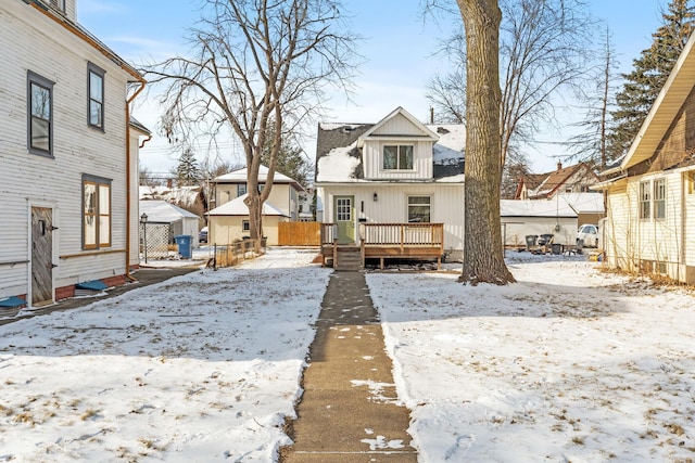 snow covered rear of property with a wooden deck