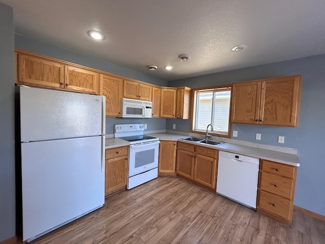 kitchen with sink, white appliances, light hardwood / wood-style flooring, and a textured ceiling