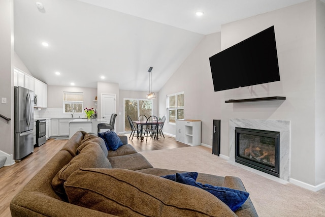 carpeted living room featuring a premium fireplace and high vaulted ceiling