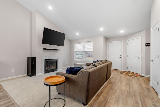 living room featuring lofted ceiling, a high end fireplace, and light hardwood / wood-style flooring