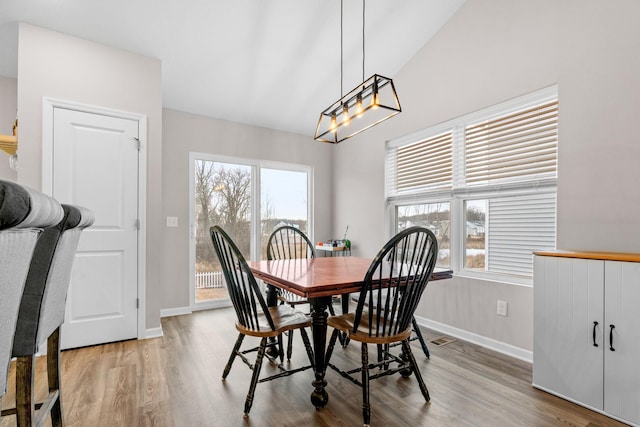 dining room with wood-type flooring and vaulted ceiling