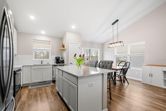 kitchen with a breakfast bar, sink, appliances with stainless steel finishes, a kitchen island, and pendant lighting