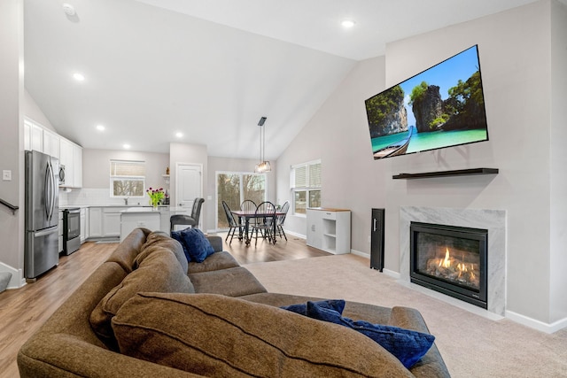 living room with a fireplace, high vaulted ceiling, and light carpet