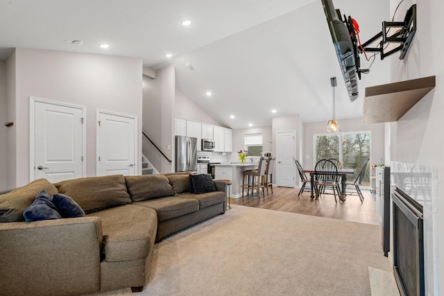 living room featuring high vaulted ceiling and light hardwood / wood-style floors