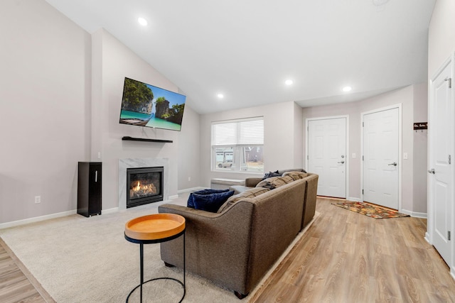 living room with lofted ceiling, a fireplace, and light hardwood / wood-style flooring