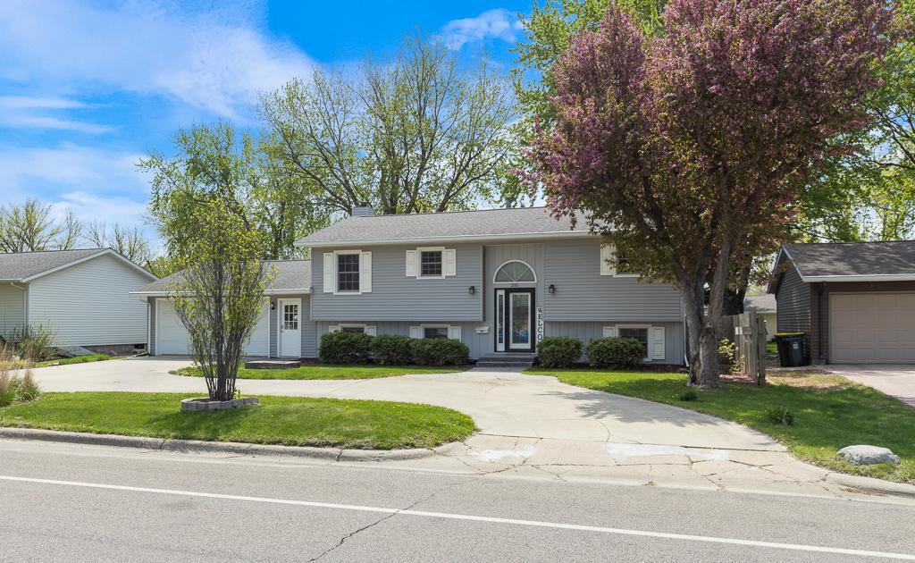 view of front facade with concrete driveway, a front yard, a chimney, and an attached garage