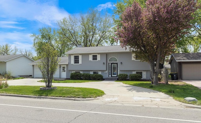 view of front facade with concrete driveway, a front yard, a chimney, and an attached garage