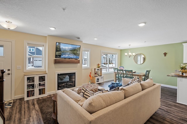 living room with an inviting chandelier, dark hardwood / wood-style floors, and a textured ceiling