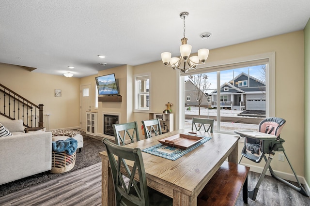 dining room with hardwood / wood-style flooring, a textured ceiling, and an inviting chandelier