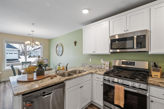 kitchen with white cabinetry, sink, stainless steel appliances, and kitchen peninsula