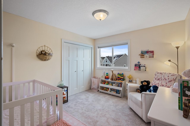 carpeted bedroom with a crib, a closet, and a textured ceiling