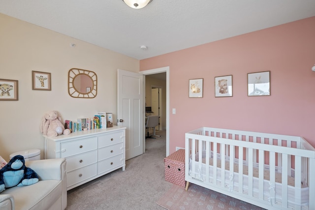 bedroom featuring a crib, light carpet, and a textured ceiling