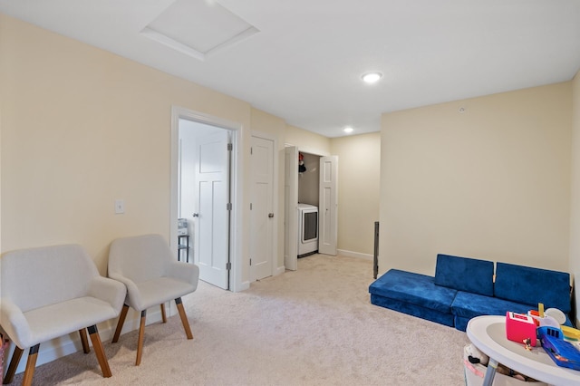 sitting room featuring light carpet and washer / dryer