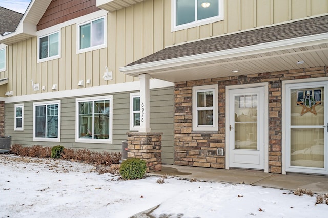 snow covered property entrance featuring central AC unit