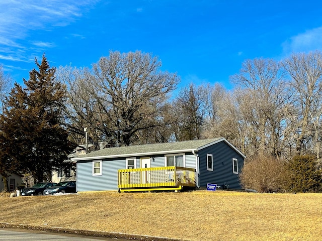 view of front of property with a deck and a front lawn