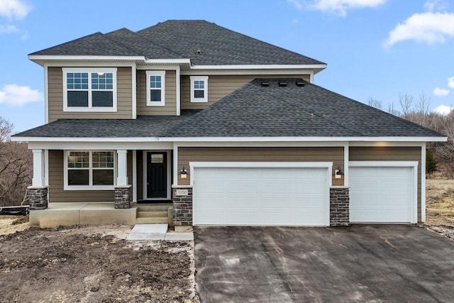view of front facade featuring an attached garage, a shingled roof, aphalt driveway, and stone siding