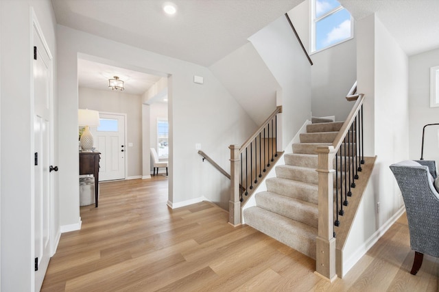 staircase featuring baseboards, a wealth of natural light, and wood finished floors
