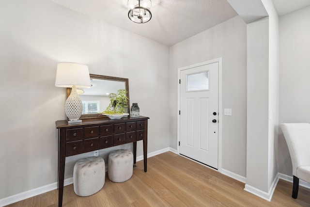 foyer entrance featuring baseboards, a wealth of natural light, and wood finished floors