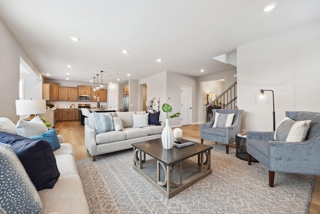 living area featuring stairs, recessed lighting, baseboards, and light wood-style floors