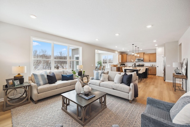 living area featuring recessed lighting, baseboards, and light wood-style floors