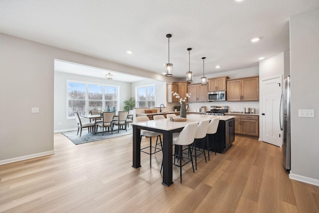 kitchen featuring appliances with stainless steel finishes, a breakfast bar area, light countertops, a center island, and recessed lighting