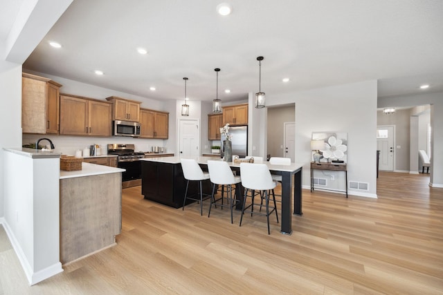 kitchen featuring light countertops, stainless steel appliances, recessed lighting, and light wood-type flooring