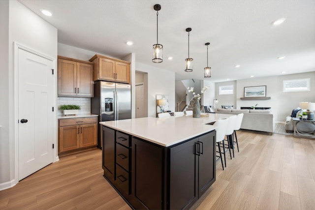 kitchen featuring light countertops, recessed lighting, open floor plan, light wood-type flooring, and stainless steel refrigerator with ice dispenser