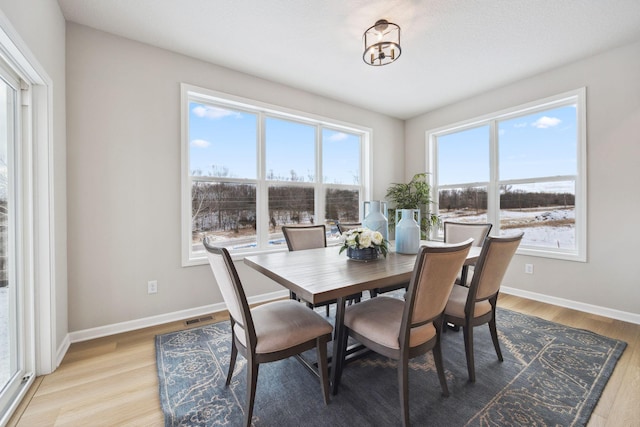 dining space featuring baseboards, visible vents, and light wood-style flooring
