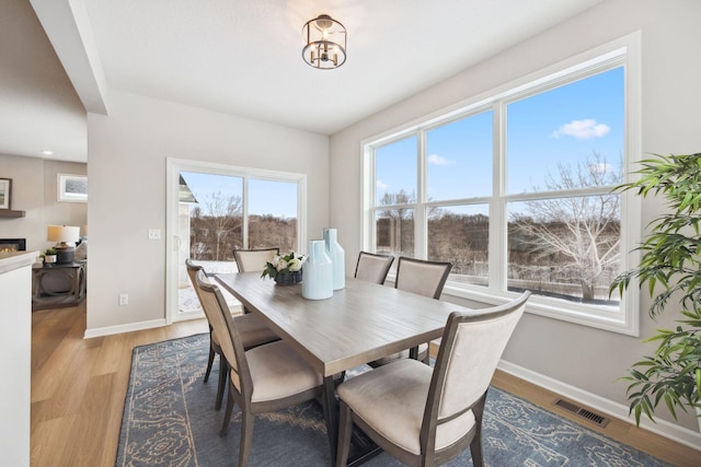 dining space featuring baseboards, light wood-style flooring, and visible vents