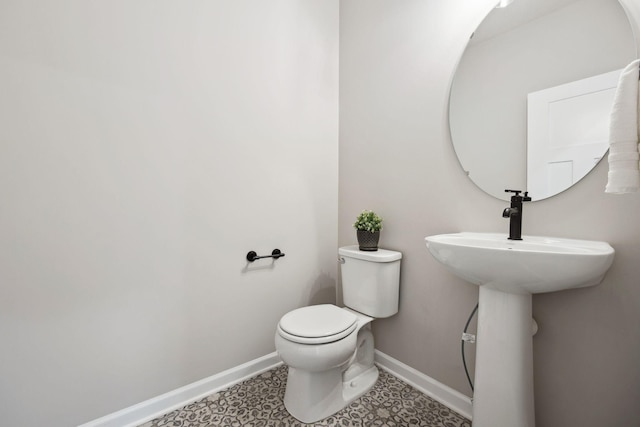 half bathroom featuring toilet and baseboards