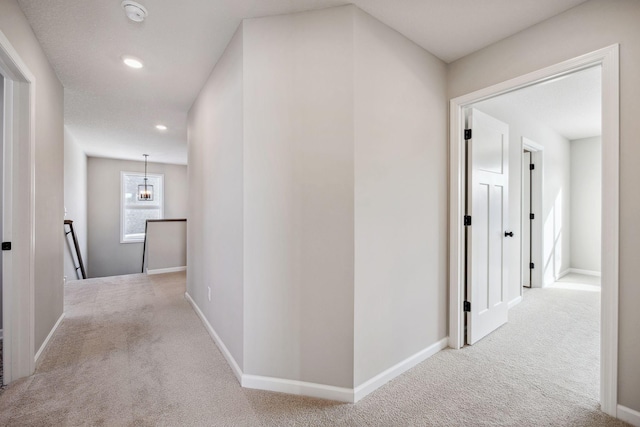 hallway with recessed lighting, carpet, baseboards, and an upstairs landing
