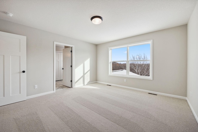unfurnished bedroom with baseboards, carpet, and visible vents
