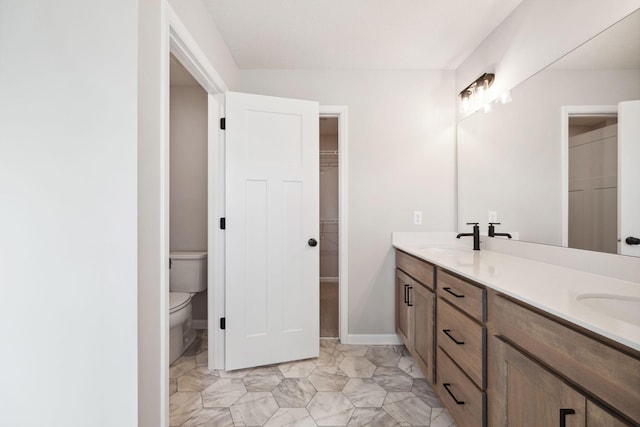 full bathroom with double vanity, toilet, a spacious closet, and a sink