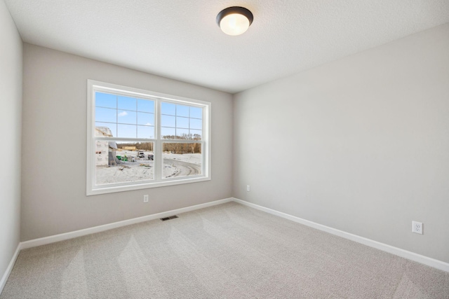 spare room with baseboards, visible vents, and carpet