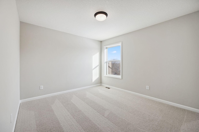 carpeted empty room featuring baseboards, a textured ceiling, and visible vents